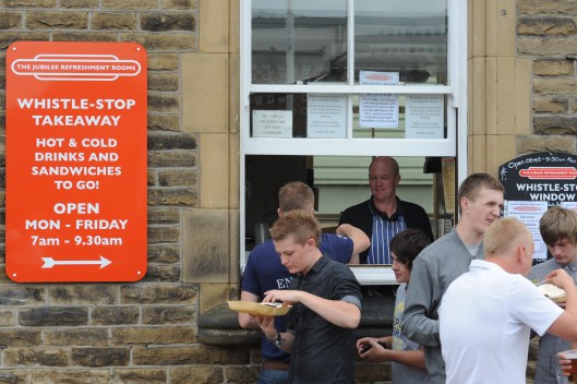 Chris Wright serves food from the 'hatch' during the annual rushbearing festival. The window is used to sell food & drink to hungry commuters every morning before the rooms open.