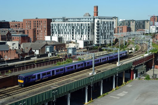 319371 is checked at signals adjacent to Salford Central station as it heads for Manchester Victoria. The city's changing skyline is evident in the picture. 